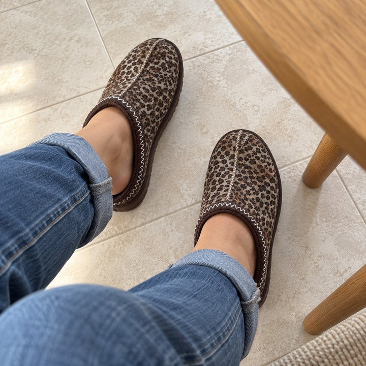 Illustrative seated wearer POV of Thin Leopard Aspen slippers.