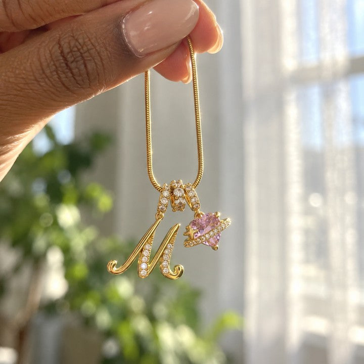 The gold Cherie initial necklace dangling from her fingertips by a window, everyday phone photo