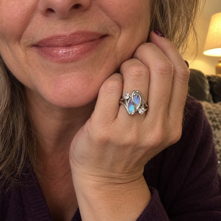 Selfie of a smiling woman resting her chin on her hand, the simulated moonstone ring on her ring finger
