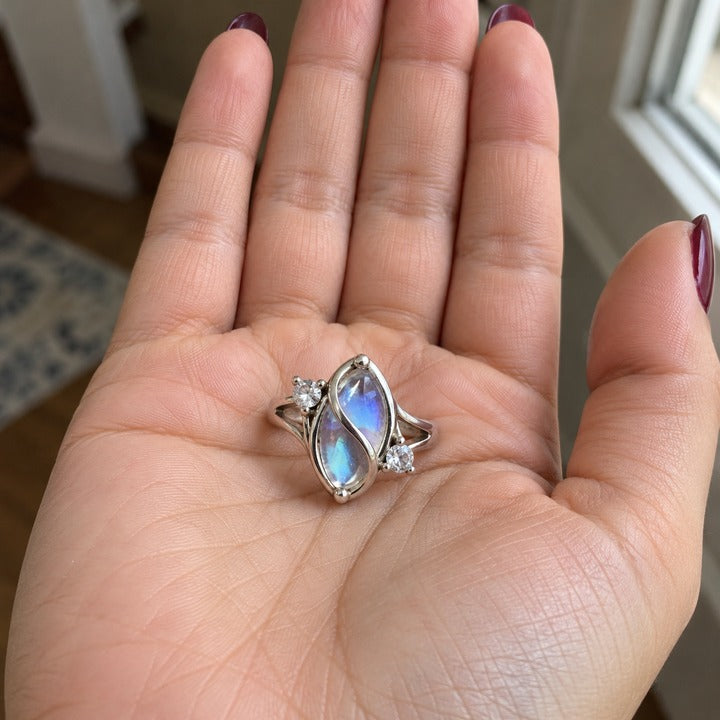 The simulated moonstone ring standing upright in an open palm