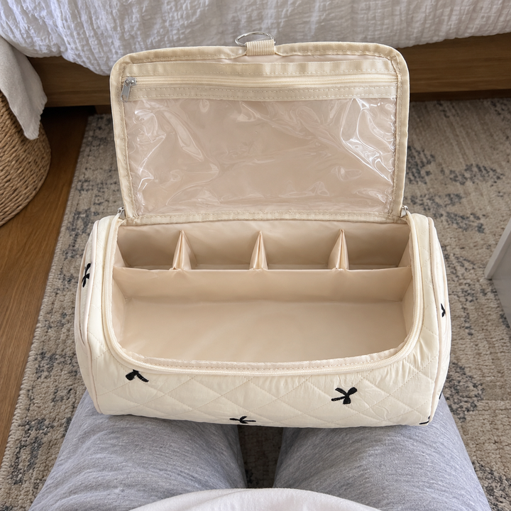 An open cream hair-tool case resting across a seated woman's lap, its compartments visible from above