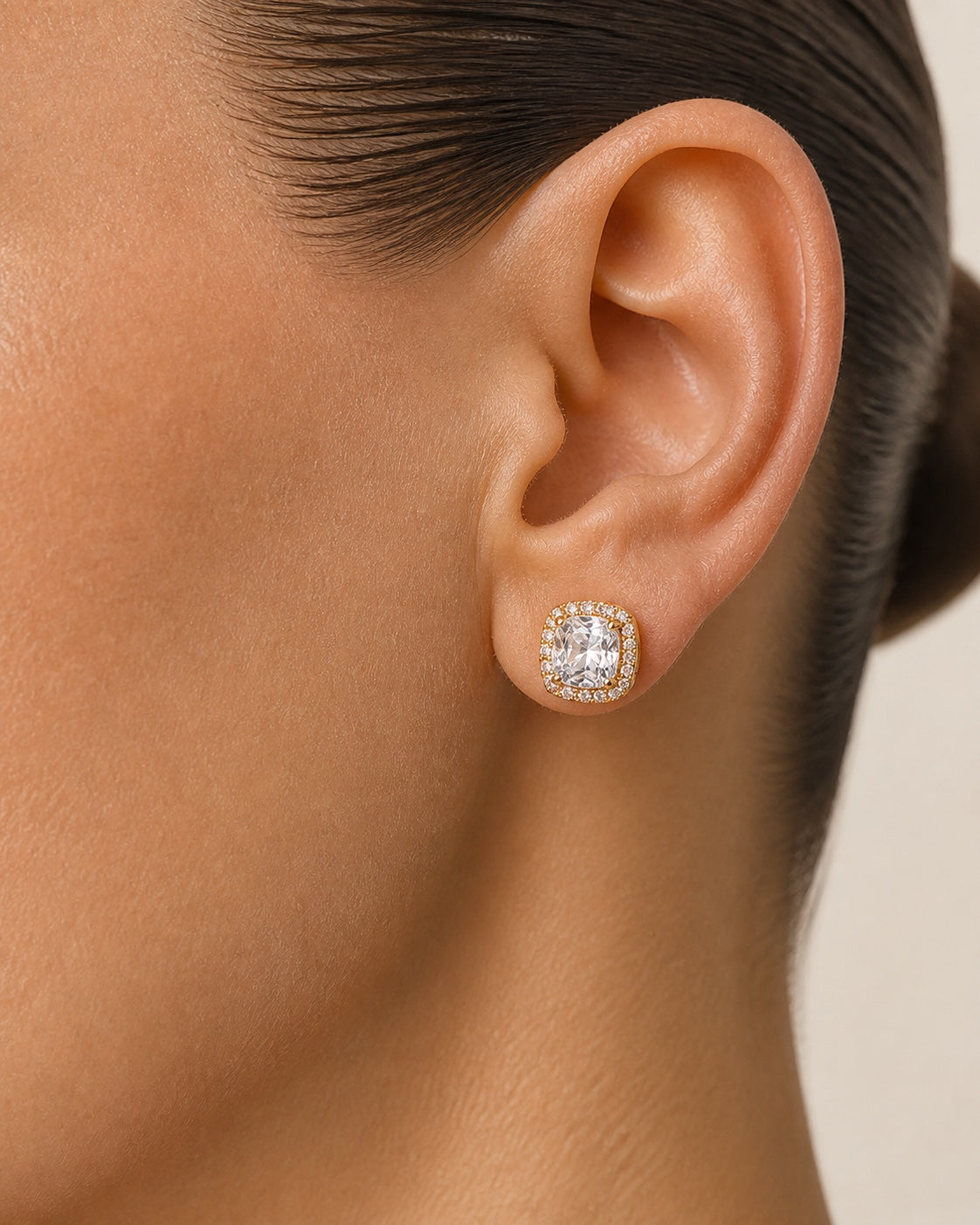 Gold square halo stud worn on the ear in a close-up view