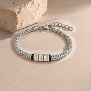 Harbor name bracelet in silver with three engraved name blocks, laid on pale stone
