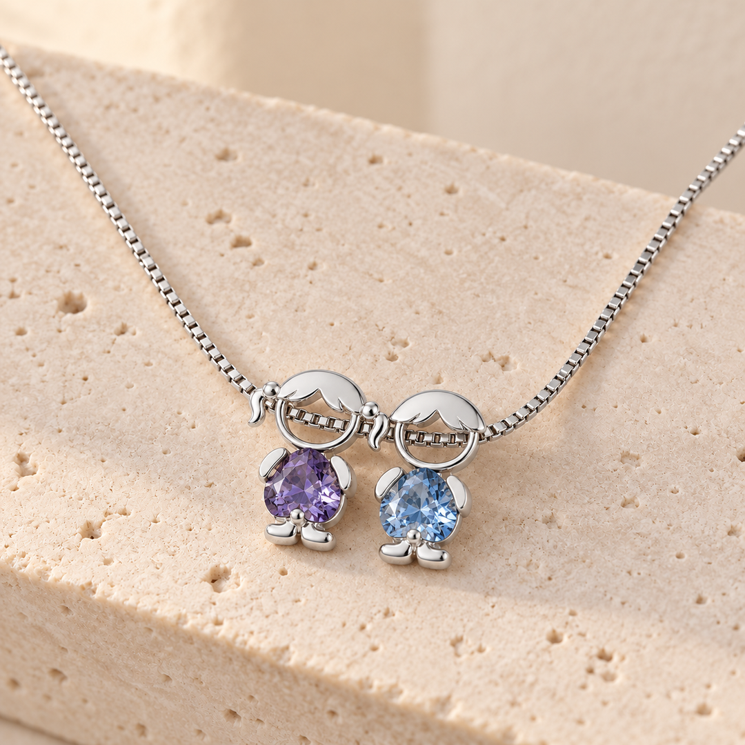 Silver-tone necklace on pale travertine with a girl and a boy charm, a violet and a sky blue heart-cut stone