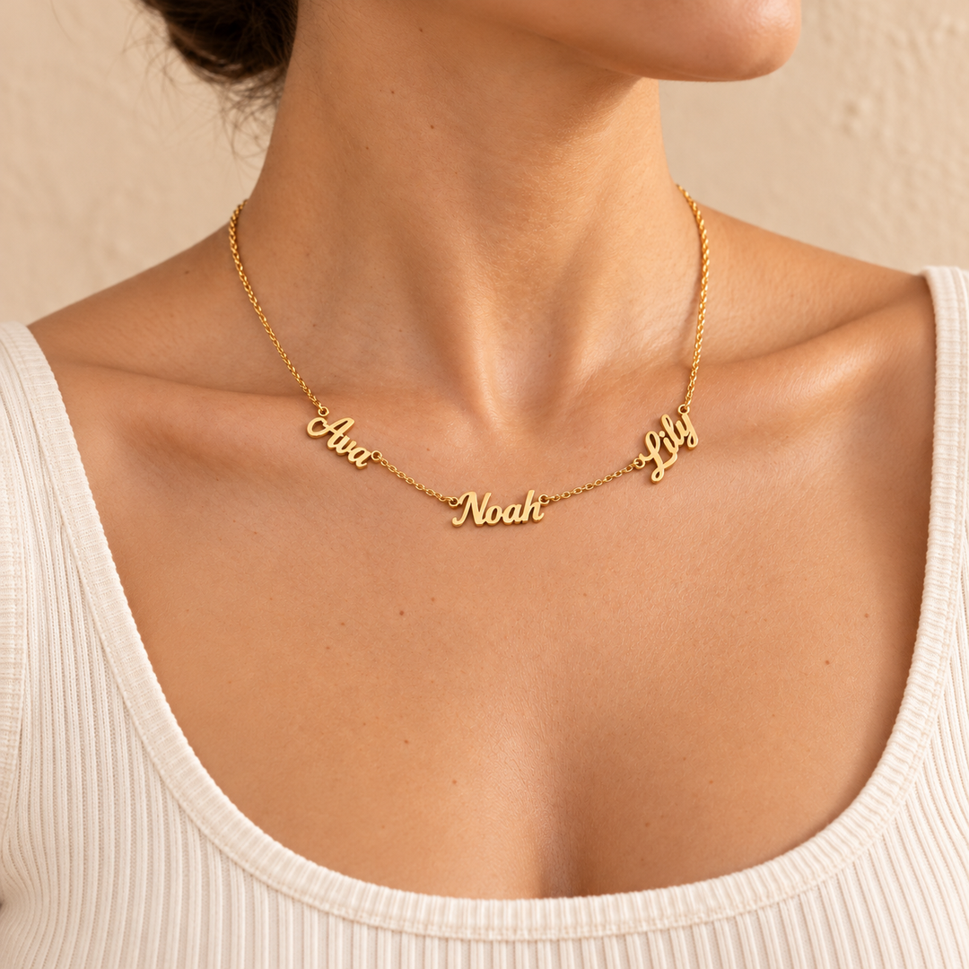 Kindred multi-name necklace in gold worn at the collarbone, three script names resting on the skin