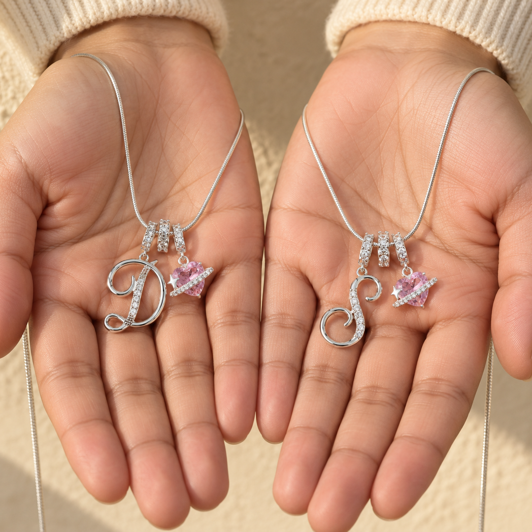 Two Cherie initial necklaces in silver held in open palms, initials D and S