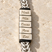 Close-up of five engraved name blocks with a stopper ring at each end, silver finish