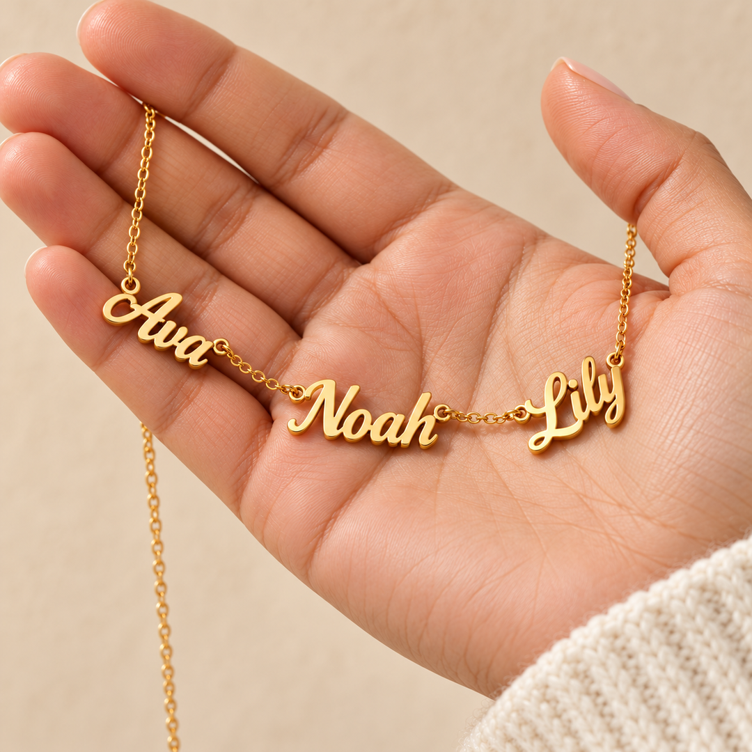 Kindred multi-name necklace in gold gathered in an open palm, three script names facing up