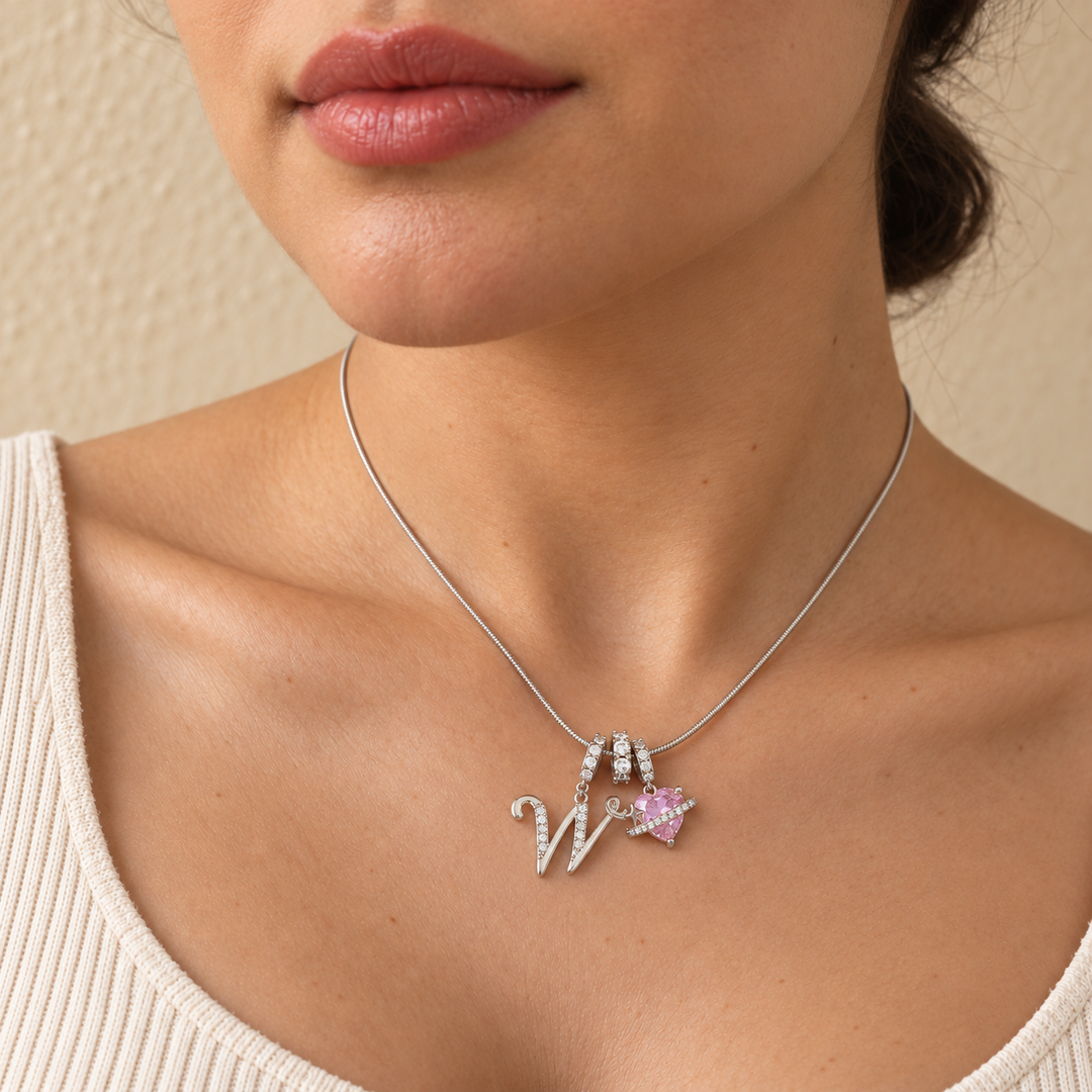 Cherie initial necklace in silver worn at the base of the neck, initial W and pink heart