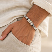 Silver Harbor name bracelet on a man's wrist, his hand in the pocket of linen trousers
