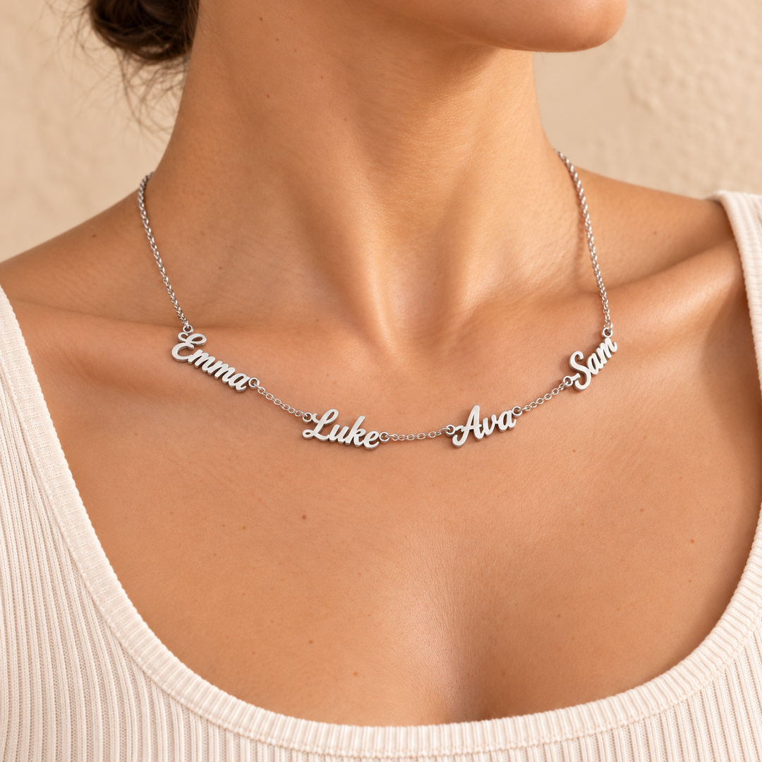 Kindred multi-name necklace in silver worn at the collarbone, four script names along the chain
