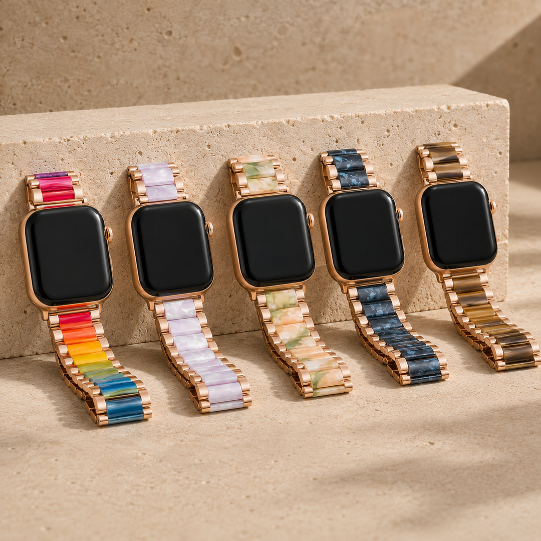 Five Adirena Metal Resin Bands for Apple Watch with Rose Gold links, one per resin design, laid apart on pale stone