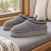 One pair of Grey Alder platform slippers on a window bench.