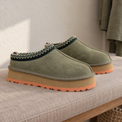 Olive Green Alder slipper pair with coral sole edges on a padded bench.