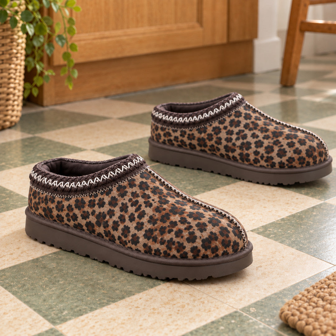 A pair of Thin Leopard Aspen slippers with rounded toes and brown soles on a tiled floor.