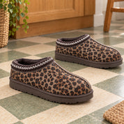 A pair of Thin Leopard Aspen slippers with rounded toes and brown soles on a tiled floor.