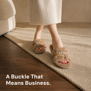 A woman standing on a woven rug in taupe fur slippers, the metal buckles level across both feet