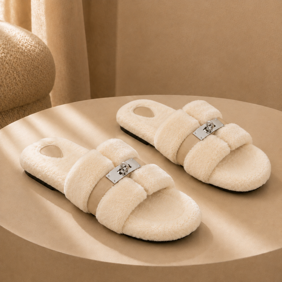 A pair of cream fur slippers on a warm plaster plinth