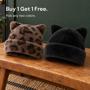 Leopard and Black Cleo cat ear hats side by side on a wooden bench, with the words Buy 1 Get 1 Free.