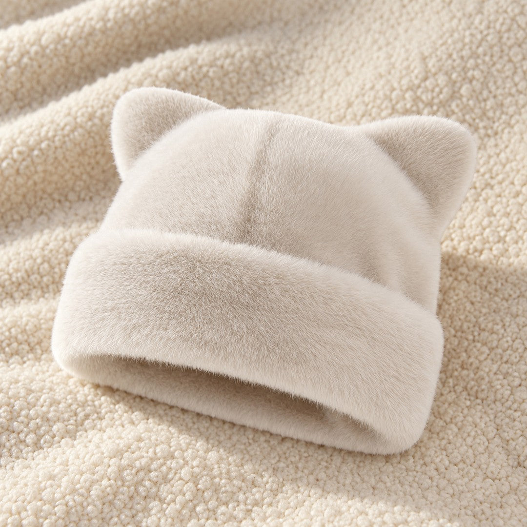 The White Cleo cat ear hat laid on a cream knit throw.