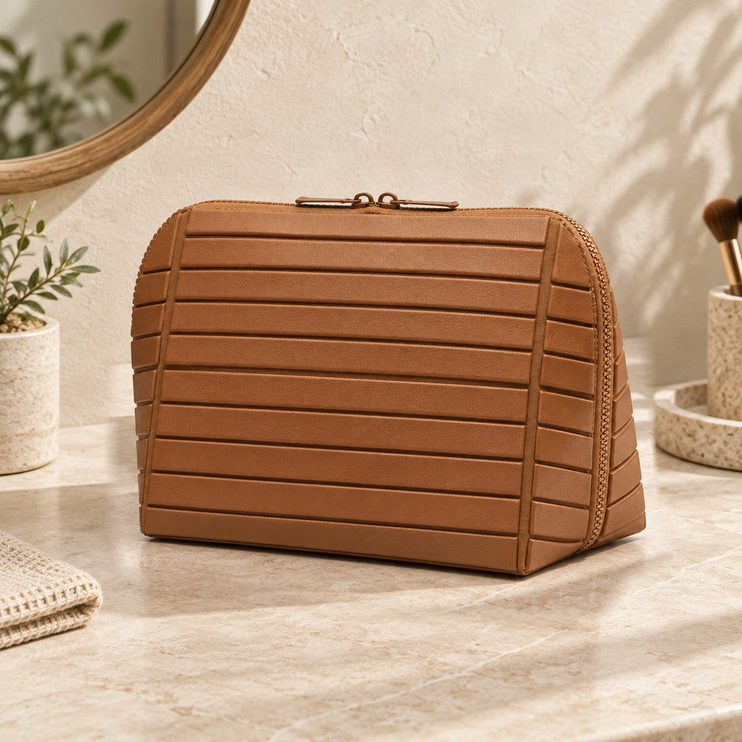 Closed brown Clara makeup bag viewed from the front on a warm vanity