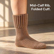A ribbed mid-calf sock worn on a bare lower leg, seen from the side on a plain floor