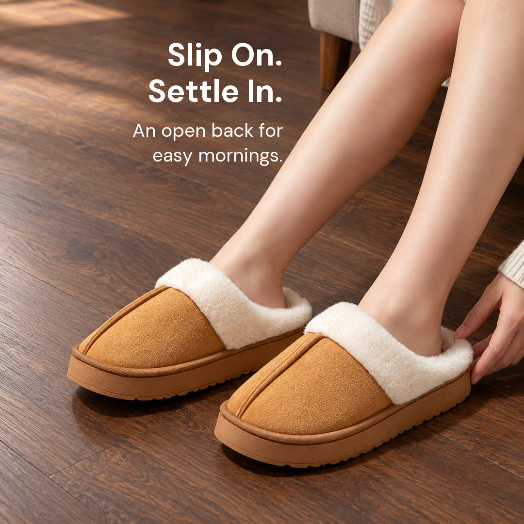 Chestnut Haven slippers worn on a dark wood floor, with fingertips beside the open back of the nearer slipper.