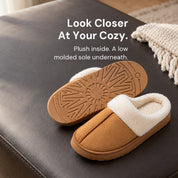 Chestnut Haven slippers on a dark upholstered ottoman, with one upright and one showing its molded outsole.