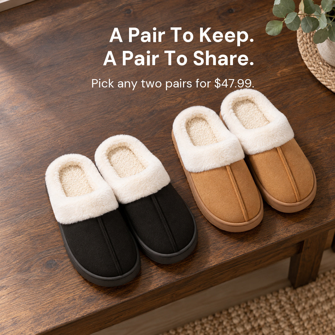 Two upright pairs of Haven slippers, one Black and one Chestnut, arranged separately on a wood table.