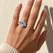 Hand raised in low sun against a plaster wall, the simulated moonstone ring's stone showing a soft blue sheen