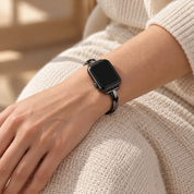 Nightglint black watch band worn on a left wrist resting on a knee