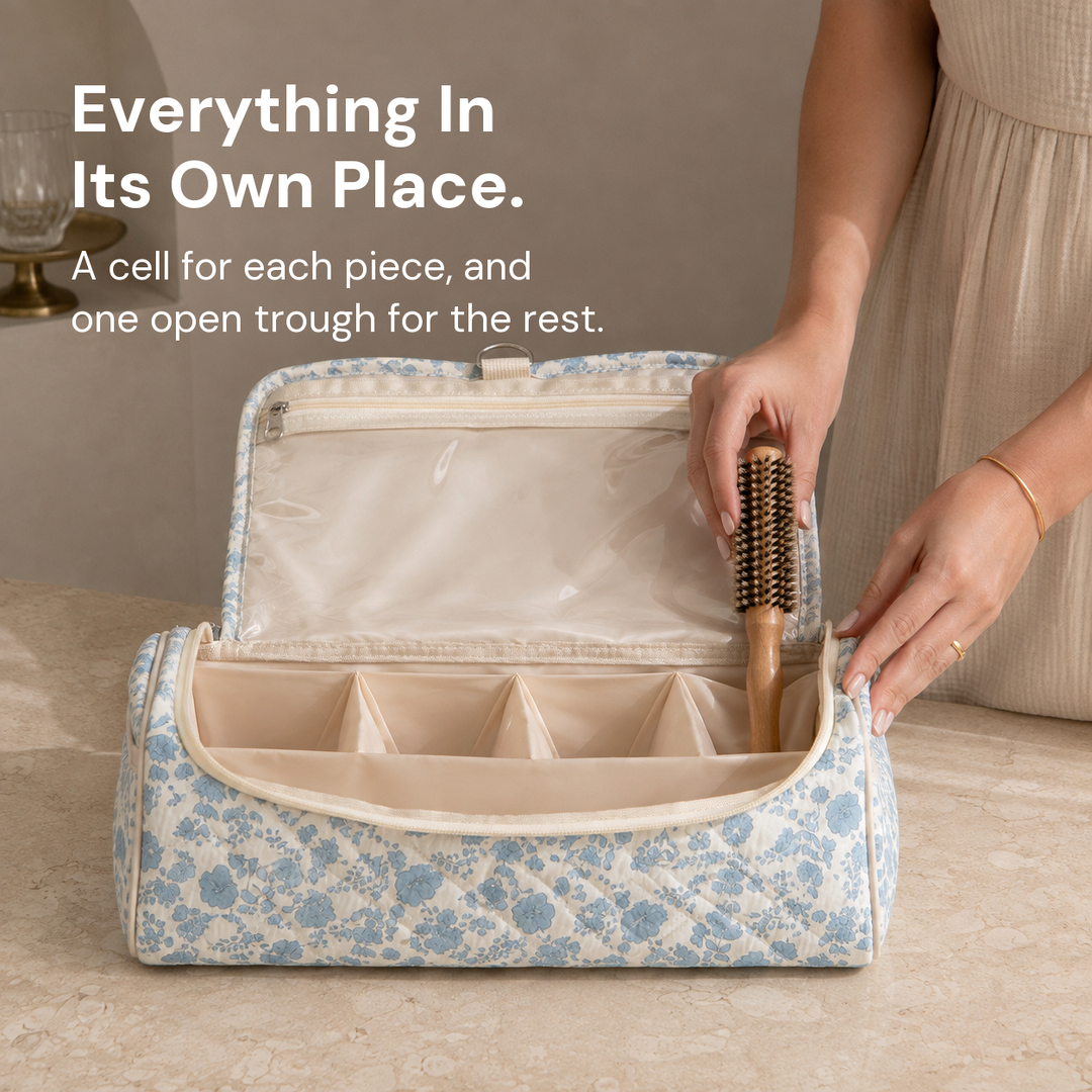 Hands settling a hairbrush into one of the divider cells of an open blue floral quilted hair-tool case