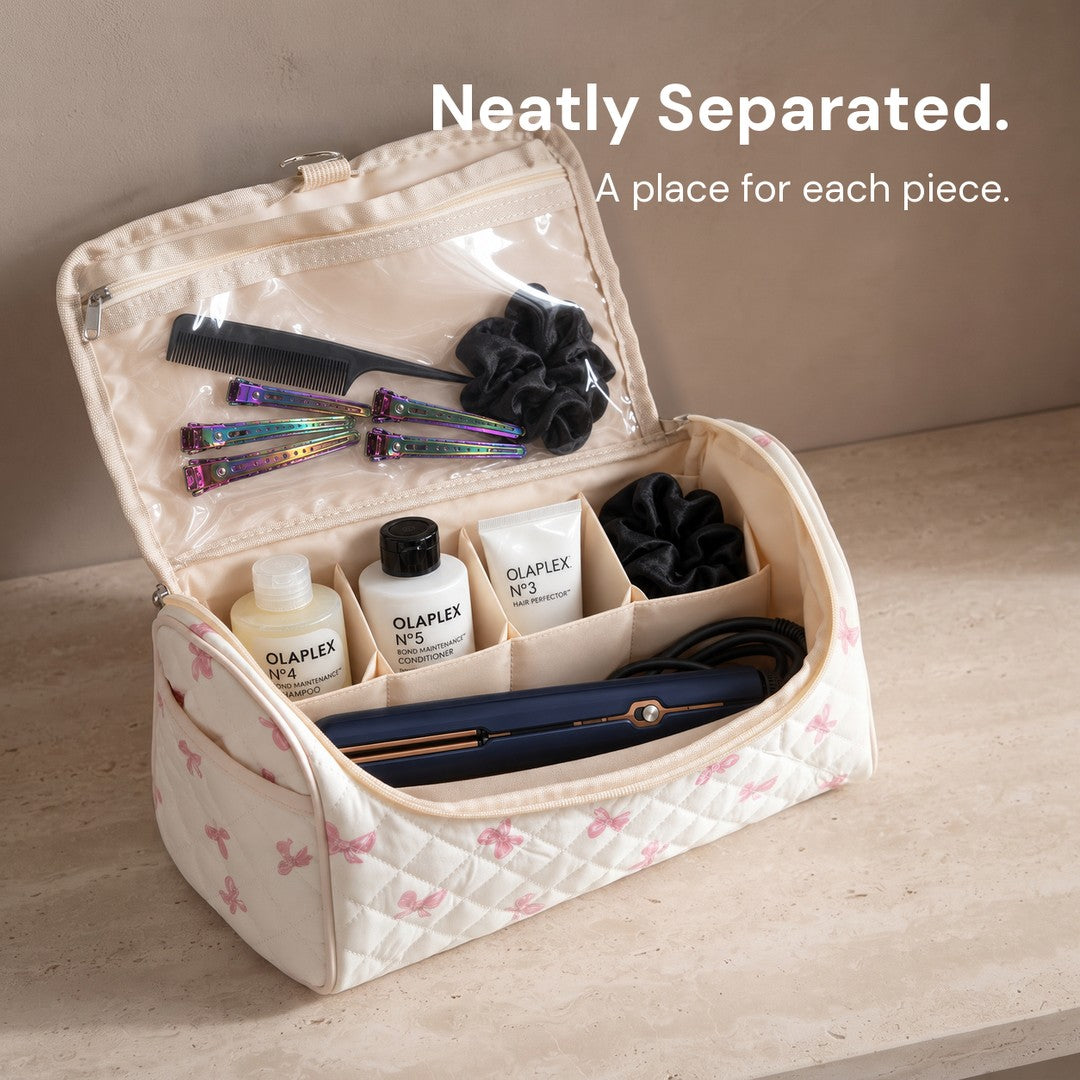 Short haircare products in the rear cells, a straightener lying in the front compartment, and accessories in the clear lid pocket of the Pink Bow Sloane bag