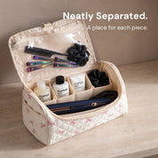Short haircare products in the rear cells, a straightener lying in the front compartment, and accessories in the clear lid pocket of the Pink Bow Sloane bag
