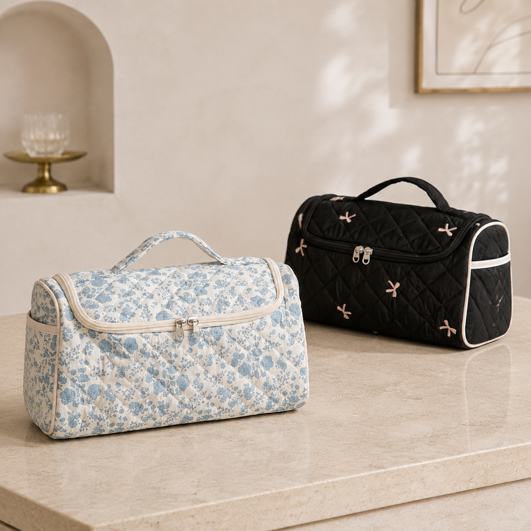 Two quilted hair-tool cases side by side on a pale stone shelf, one in blue floral and one in black with embroidered bows