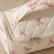 Close-up of the two silver zip sliders and the stitched-down handle on a quilted hair-tool case