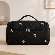 A quilted hair-tool case in the black bow pattern, closed and seen straight on