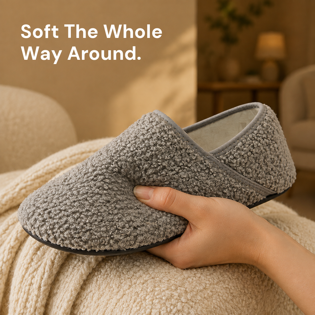 A hand holding one grey slipper sock, showing the looped bouclé surface up close