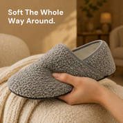 A hand holding one grey slipper sock, showing the looped bouclé surface up close
