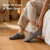 One bare foot and one sock-covered foot, each in a slipper sock