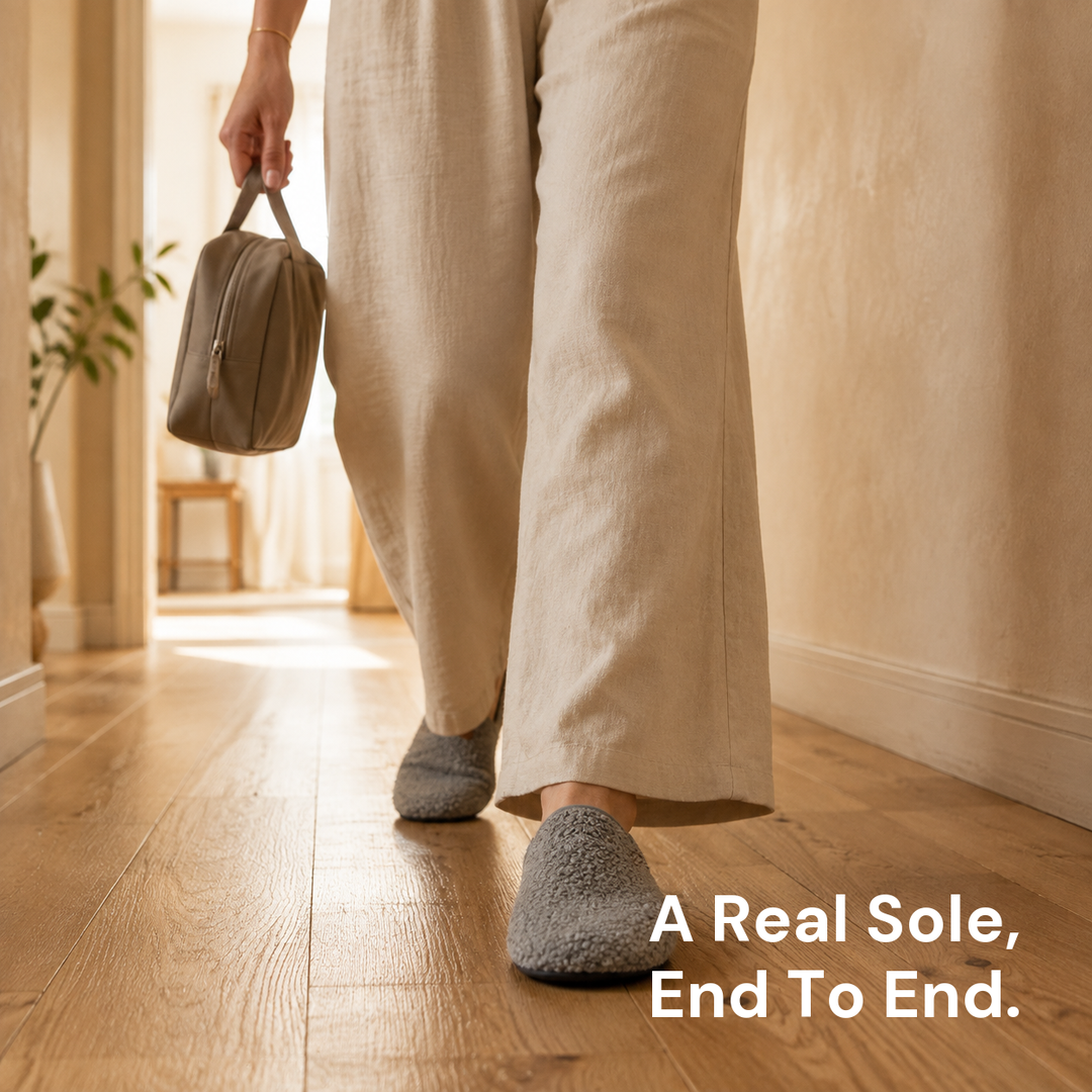 A foot mid-step along a corridor wearing a grey slipper sock