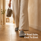 A foot mid-step along a corridor wearing a grey slipper sock