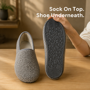 One slipper sock upright beside another turned to show its rubber sole