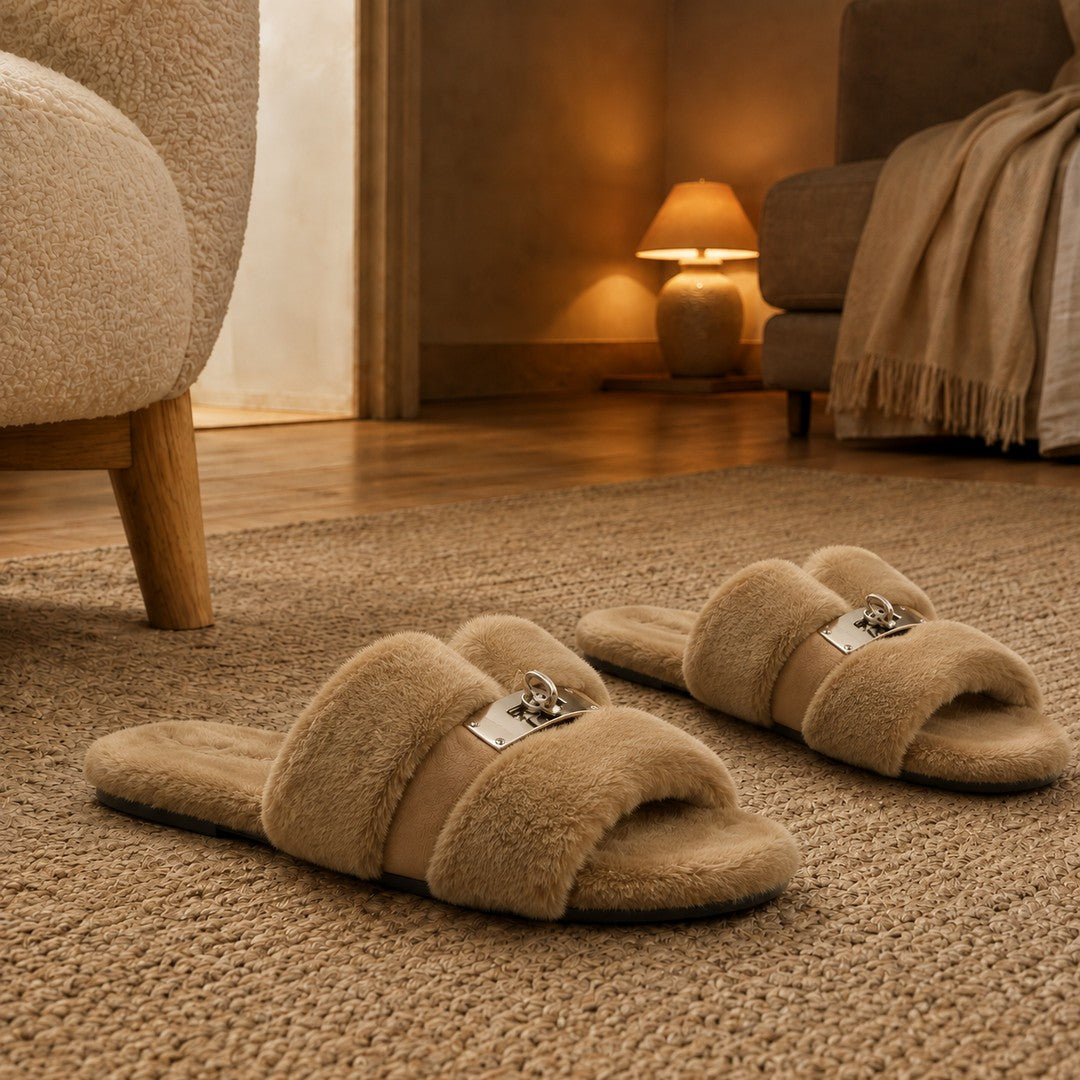 A pair of taupe fur slippers set neatly on a rug beside a chair in warm evening light