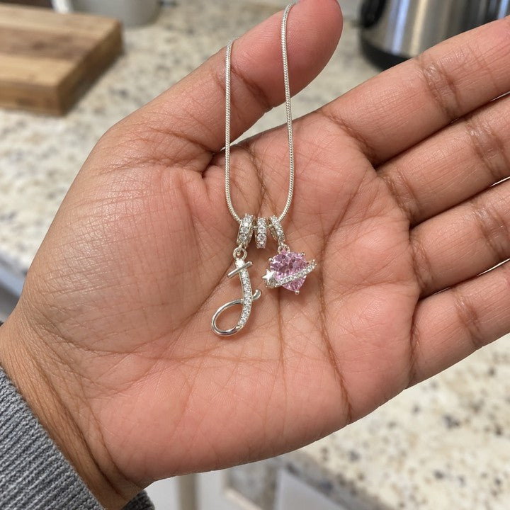 A hand holding the silver Cherie initial necklace, everyday phone photo