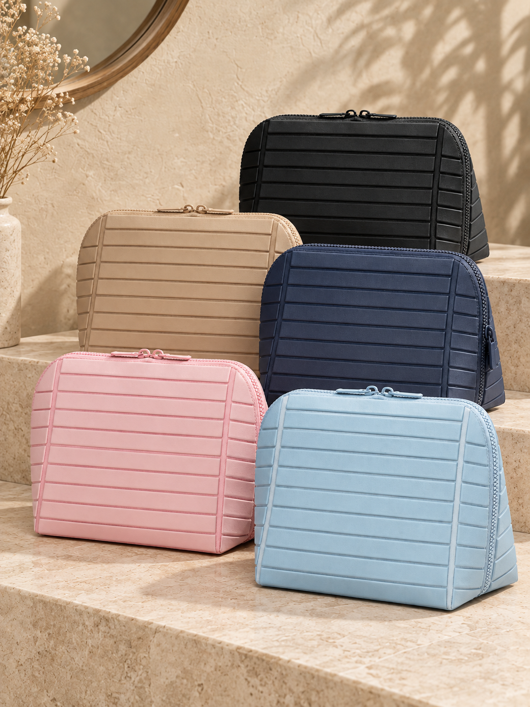 Five separate Clara makeup bags in pink, apricot, light blue, black and navy