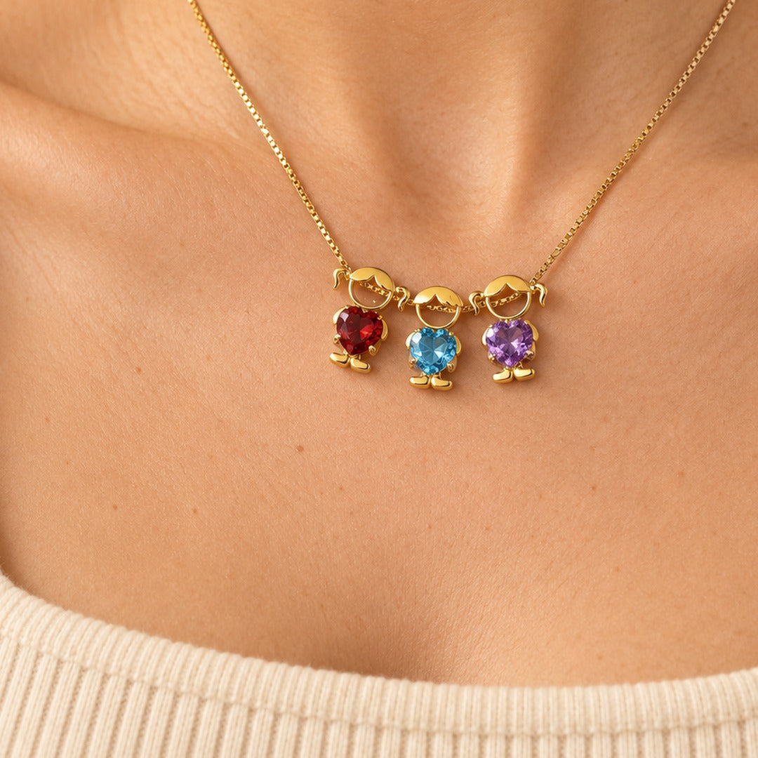 Three charms of the gold-tone necklace resting on the chest, with deep red, sky blue and violet heart-cut stones