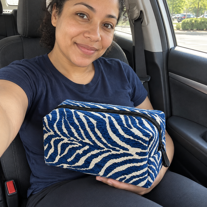 AI illustration: a woman seated in a car holds a closed blue zebra pouch across her lap.