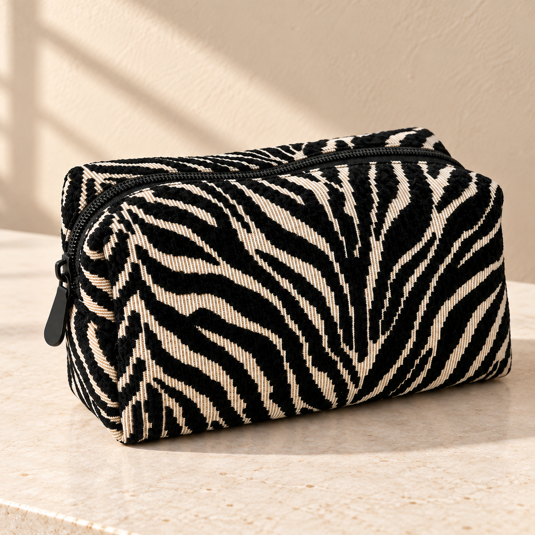 Close view of the raised black and cream zebra weave and dark zipper on a closed pouch.